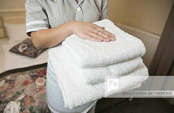 Close up weiblichen Zimmermädchen hält sauberen weichen gefalteten Handtuch Hand