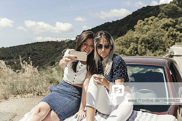 Trendy weibliche Freunde sitzen Auto nehmen selfie