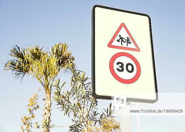 Close up Fußgänger Warnschild mit 30 Geschwindigkeitsbegrenzung Zeichen gegen grünen Baum blaün Himmel