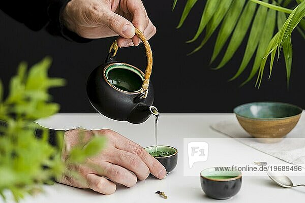 Mann gießt Tee ein Teetasse