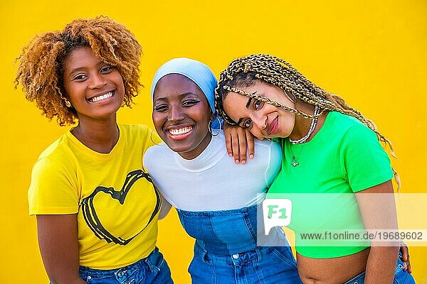 Close up Porträt von drei Frauen verschiedener Ethnien  die in die Kamera lächeln  vor einem gelben Hintergrund