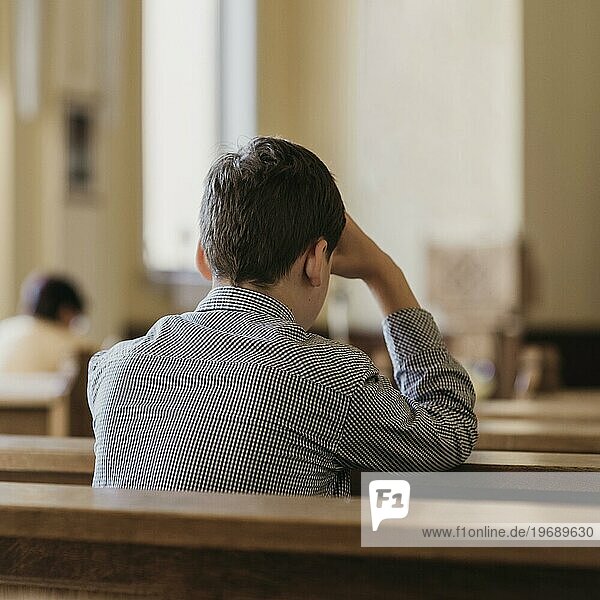 Rückenansicht junger Mann beim Beten in der Kirche