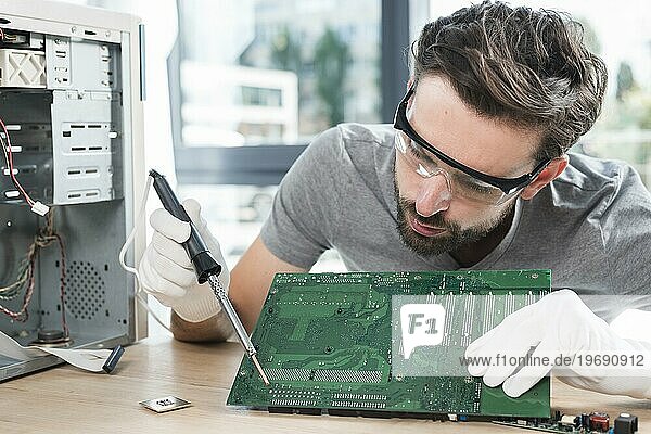 Männlicher Techniker repariert Computerplatine