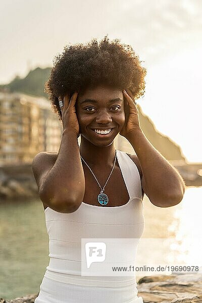 Vertikales Porträt einer glücklichen afrikanischen Frau  die neben dem Meer in die Kamera blickt