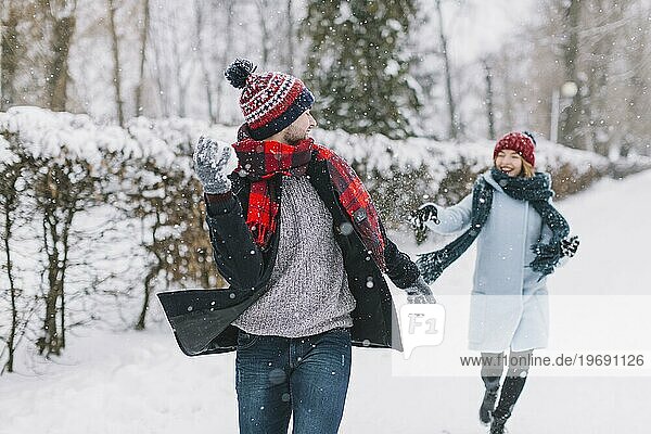 Zufriedenes Paar spielt Schneebälle im Park