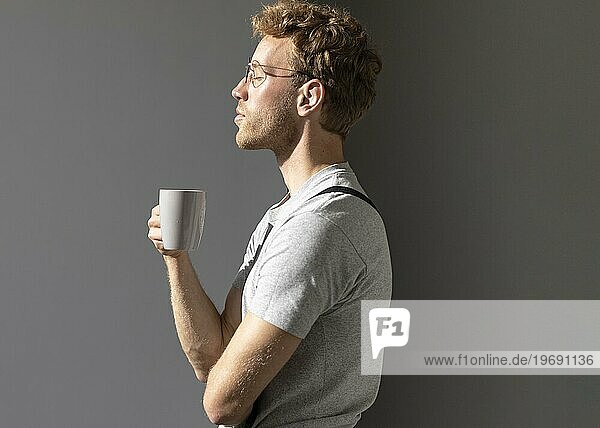 Seitlich stehender Mann trinkt seinen Kaffee