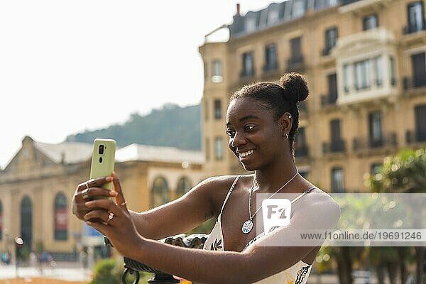 Seitenansicht einer süßen afrikanischen jungen Frau  die ein Selfie auf der Straße macht