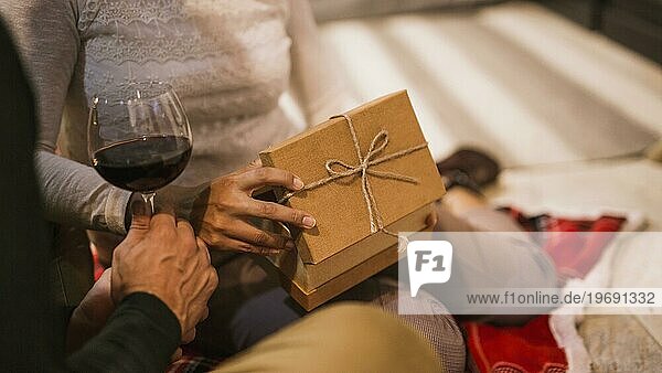 Paar öffnet gemeinsam Geschenke bei einem Glas Wein