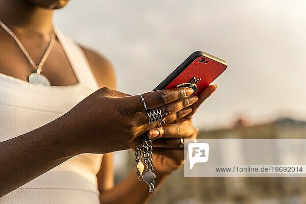 Close-up of the hands of a stylish afro woman using phone outdoors