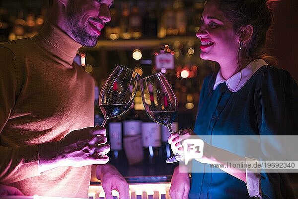 Glücklicher Mann klirrt Gläser Wein mit fröhlicher Frau