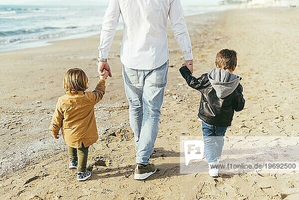 Kinder gehen mit Papa am Strand spazieren
