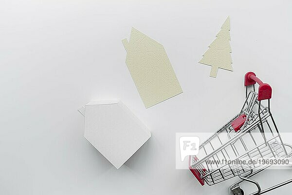 Papier ausgeschnitten Haus Weihnachtsbaum mit Miniatur Haus Modell Einkaufswagen isoliert weißem Hintergrund