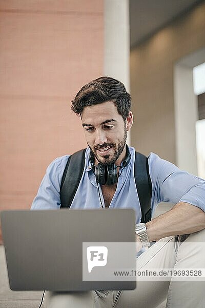 Nahaufnahme eines glücklichen männlichen Touristen  der einen Laptop benutzt