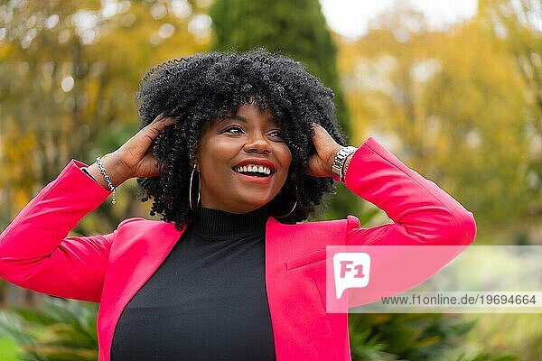 Stilvolle afroamerikanische Geschäftsfrau posiert fröhlich im Freien in einem Stadtpark