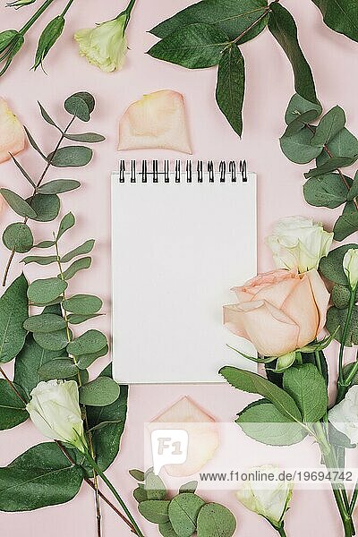Blanko Spirale Notizblock mit rosa Eustoma Blumen vor rosa Hintergrund