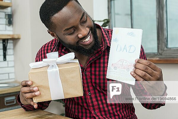 Glücklicher schwarzer Mann hält Grußkarte Geschenk