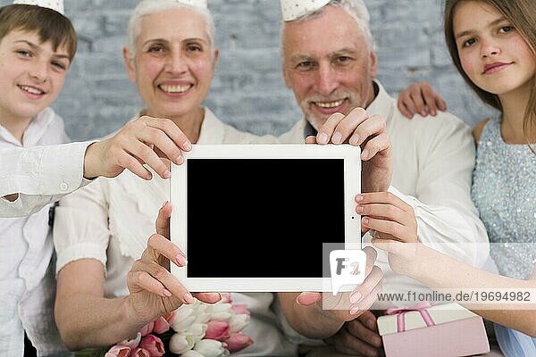 Glückliche Familie zeigt leeren Bildschirm digitales Tablet