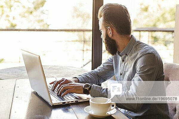 Seitenansicht Mann tippt Laptoptastatur mit Tasse Kaffee Schreibtisch