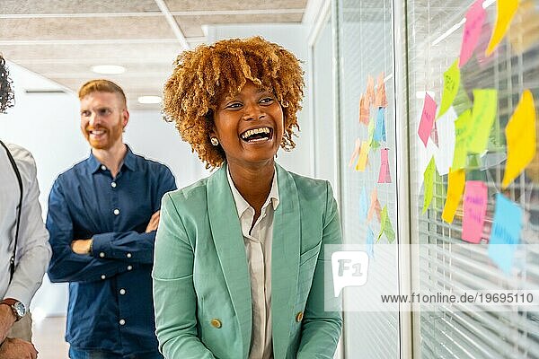 Glückliche afrikanische Frau lächelt während eines kreativen Prozesses in einem Coworking