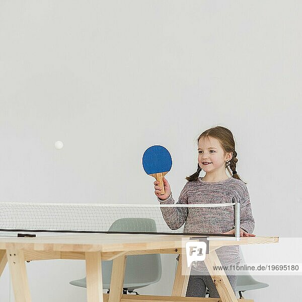 Entzückendes Kind spielt drinnen Tischtennis