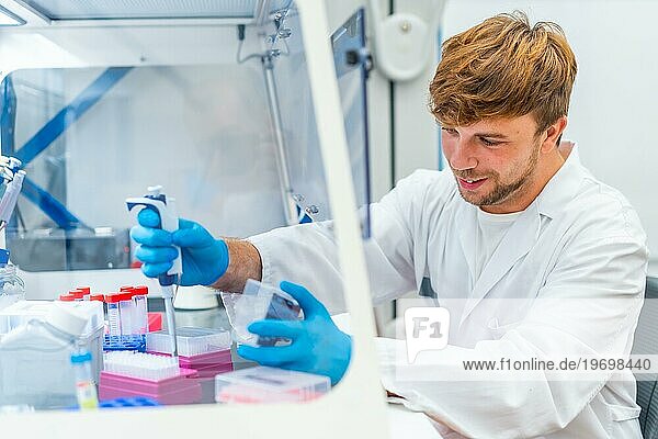 Seitenansicht eines jungen und fröhlichen Wissenschaftlers  der medizinische Proben in eine Mikroplatte im Labor pipettiert