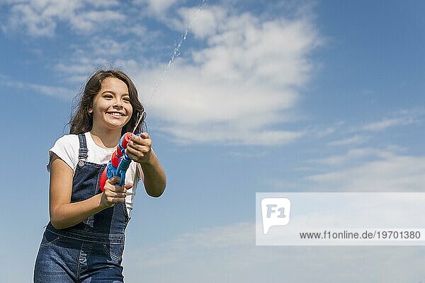 Vorderansicht kleines Mädchen spielt mit Wasserpistole draußen