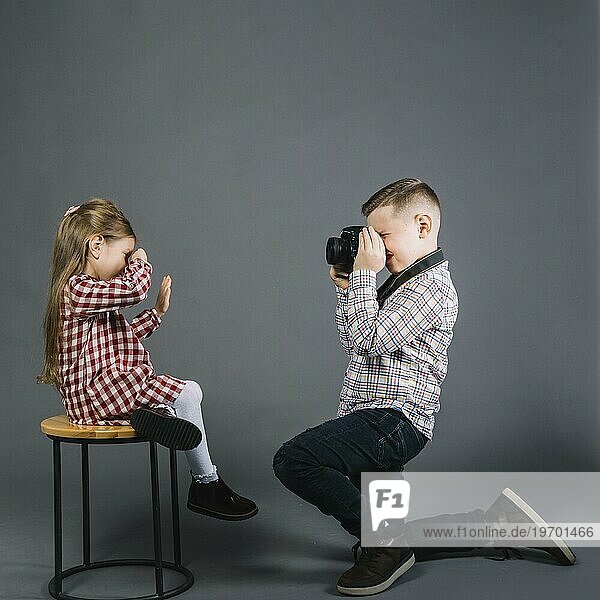 Seitenansicht Junge nimmt Mädchen sitzend Hocker mit Kamera