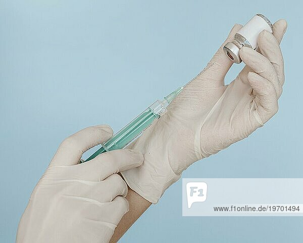 Hände mit Handschuhen halten Spritze mit Impfstoffflasche