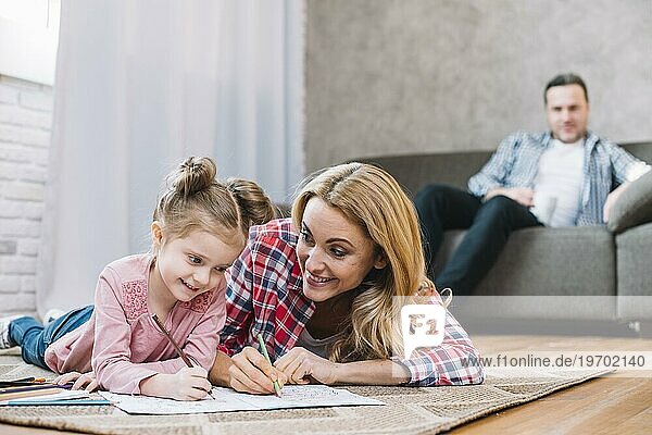 Unscharfe Fokus Vater schaut ihre Frau Tochter beim Zeichnen Buch