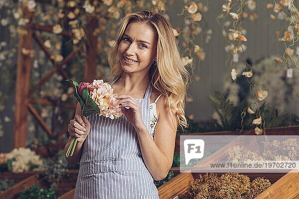 Porträt lächelnd blonde Blumenhändlerin hält Blumenstrauß Hand