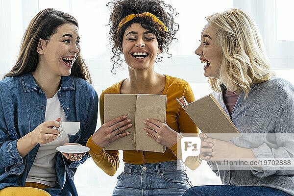 Drei Frauen lachen zusammen mit einem Buch
