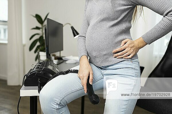 Seitenansicht schwangere Geschäftsfrau sitzt Schreibtisch hält Telefonhörer