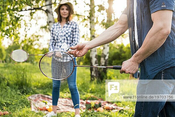 Junges Paar spielt Badminton beim Picknick