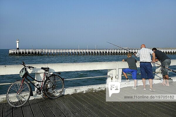 Sohn  Vater und Großvater beim Angeln mit der Angelrute vom Pier an der Nordseeküste in Nieuwpoort  Nieuport  Belgien  Europa