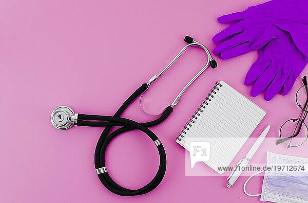 Stethoskop chirurgische Handschuhe Brille Stift Spirale Notizblock rosa Hintergrund