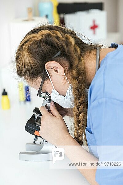 Ärztin schaut durch ein Mikroskop im Labor