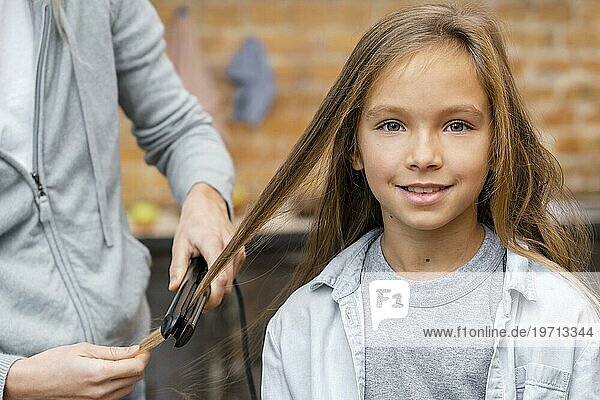 Kleines Mädchen  das vom Friseur die Haare geglättet bekommt