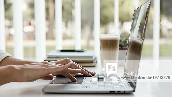 Seitenansicht Geschäftsfrau arbeitet mit Laptop und trinkt Kaffee