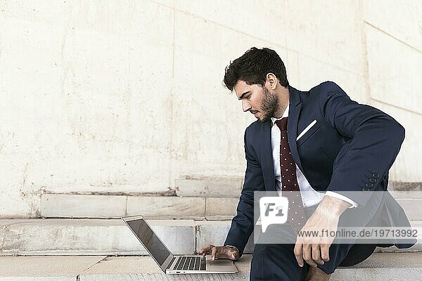 Mittlere Einstellung Mann sitzt auf einer Treppe mit Laptop