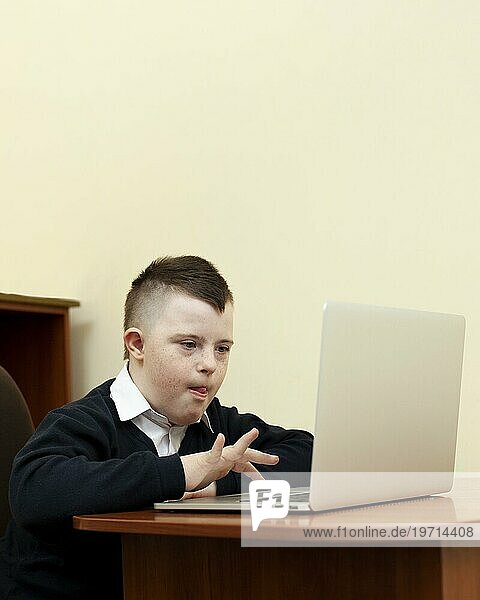 Seitenansicht Junge mit Down Syndrom schaut auf Laptop
