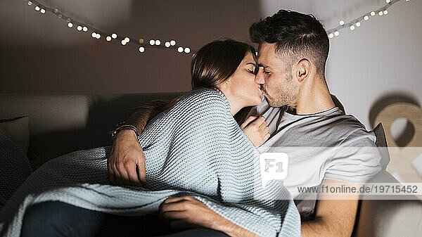 Junger Mann küsst mit Frau auf dem Sofa liegend