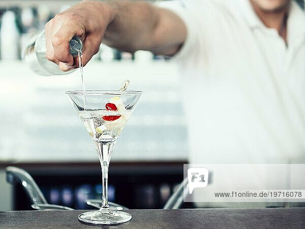 Unbekannter Barmann schenkt Cocktailglas ein