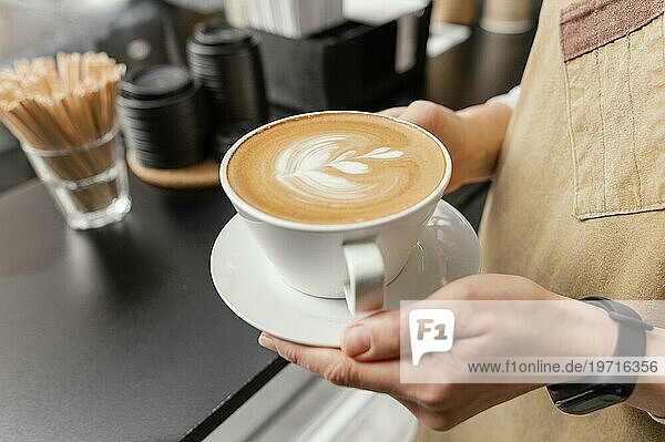 Seitenansicht weibliche Barista hält dekorierte Tasse Kaffee Hände