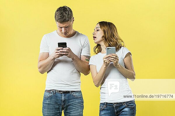 Verdächtige Freundin spioniert seinen Freund SMS Handy gegen gelben Hintergrund