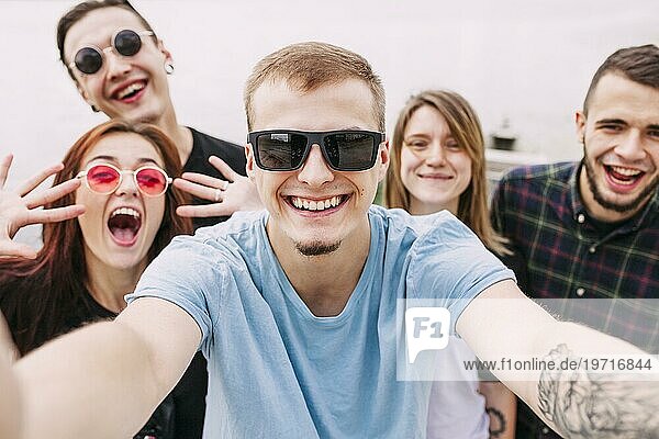 Porträt lächelnder Mann nimmt Selfie mit Freunden