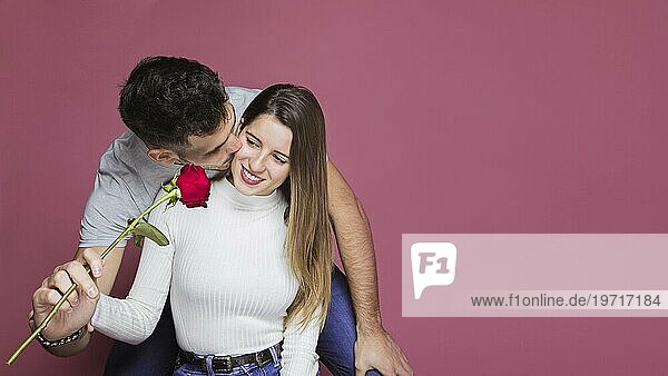 Guy küssen präsentiert frische Rose attraktiv fröhliche Dame