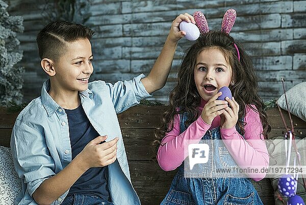 Mädchen Hasenohren Junge spielt mit Ostereiern