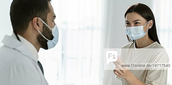 Patient und Arzt im Gespräch  während er medizinische Masken trägt