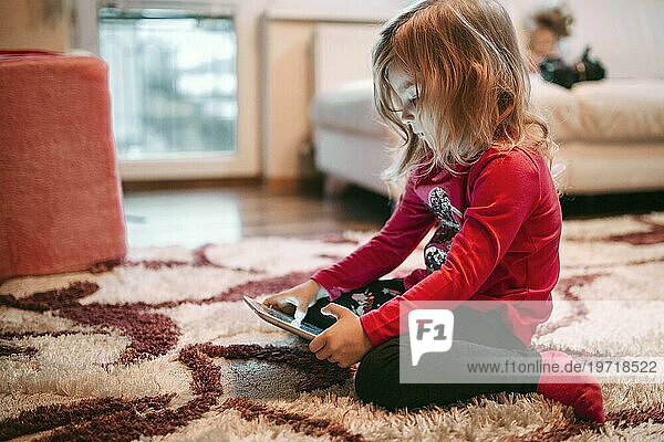 Mädchen spielt Tablet Spiel Boden