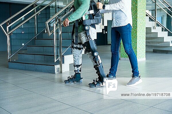 Mechanisches Exoskelett  Physiotherapeut  der mit einer nicht wiederzuerkennenden behinderten Person mit Roboterskelett geht  Physiotherapie in einem modernen Krankenhaus: